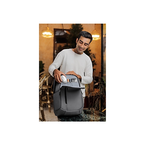 Ein Mann mit weiÃŸem Pullover Ã¶ffnet einen grauen Rucksack.