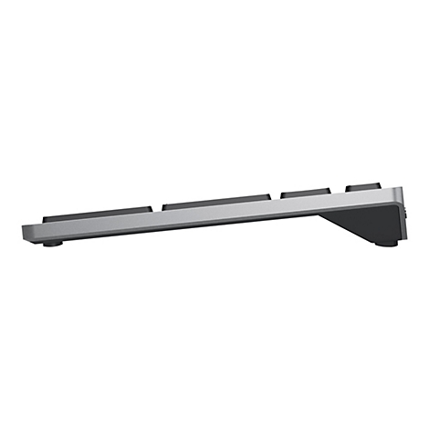 Vue latérale d'un clavier gris avec des touches noires. Le clavier est légèrement incliné et repose sur de petits pieds.