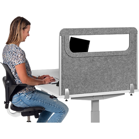 Woman typing at desk. Gray privacy screen with window on table.