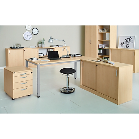 A modern office with a desk, mobile pedestal, chair, lamps, filing cabinets, and clocks on the wall.