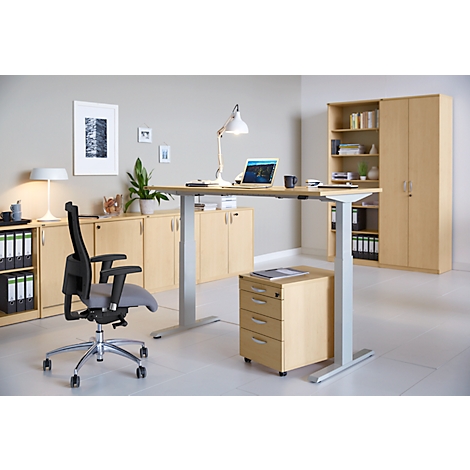 Office with height-adjustable desk, swivel chair, sideboard, and cabinet. Laptop, lamp, and cup on the desk.