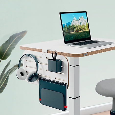 Desk with laptop, headphones, and notebook. Background: light green. A mountain landscape is visible on the laptop.