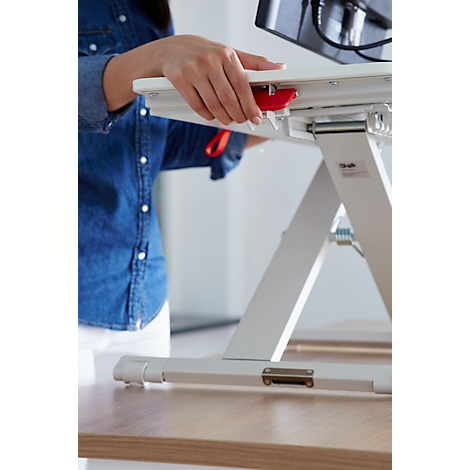 Close-up of a hand operating a red lever on a height-adjustable desk.