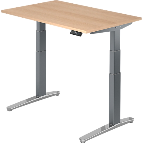 A height-adjustable desk with a light brown tabletop and gray metal legs. The desk has a control unit.