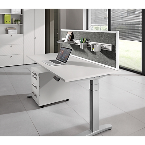 White height-adjustable desk with laptop, gray felt board, pen holders, and cabinet. In the background: white cabinet.