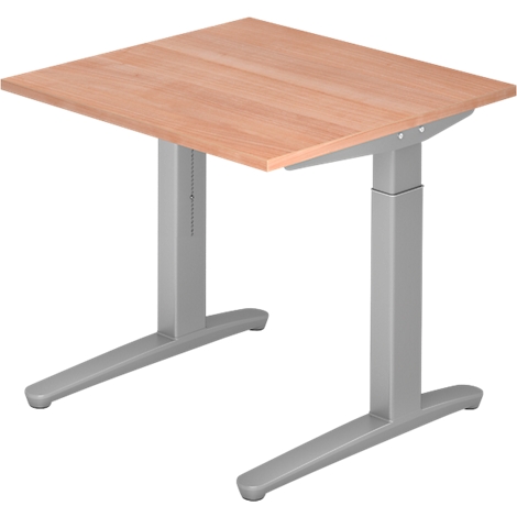 A height-adjustable desk with a light brown tabletop and grey metal legs. The tabletop is rectangular and the legs are T-shaped.