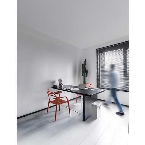Bureau avec bureau, chaises et cactus. Une personne floue passe. Aspect bois clair et fenêtre avec stores.