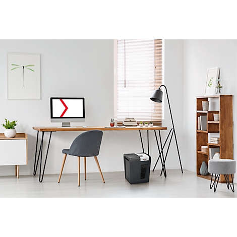 Espace de travail lumineux avec bureau, chaise, ordinateur, déchiqueteuse et bibliothèque. Stores et lampadaire près de la fenêtre.