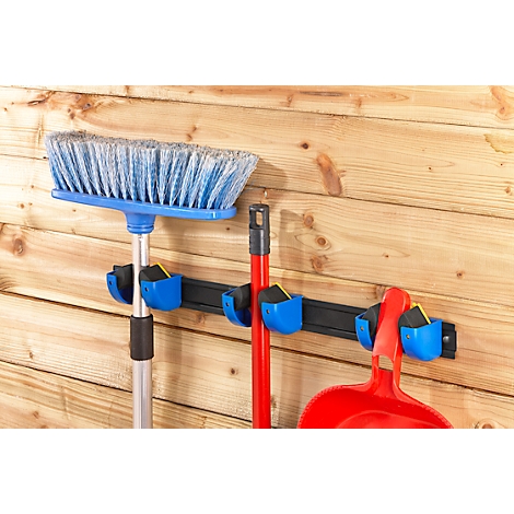 Broom, shovel and dustpan set in blue holders on a wooden plank wall.