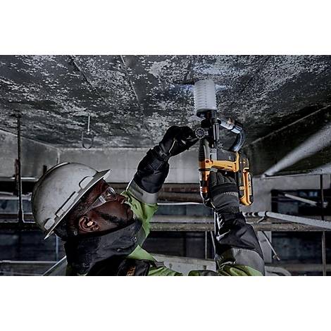 Un homme portant un casque de chantier perce un plafond avec une perceuse jaune.