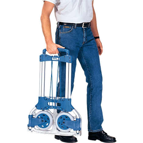 Une personne tient un chariot pliable bleu et argenté. Les roues sont visibles, la personne porte un jean.