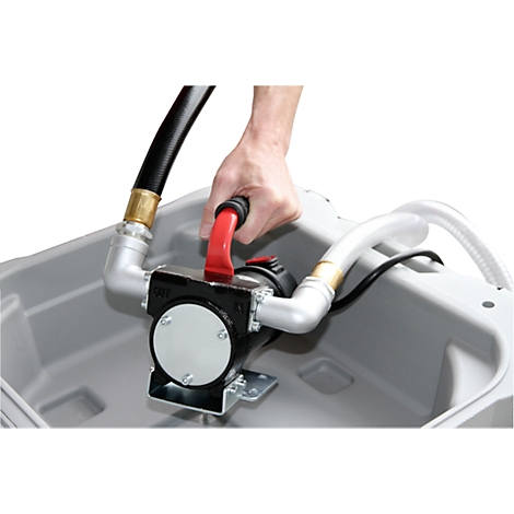 A hand holds a red pump on a black motor with hoses. The pump is in a gray container.