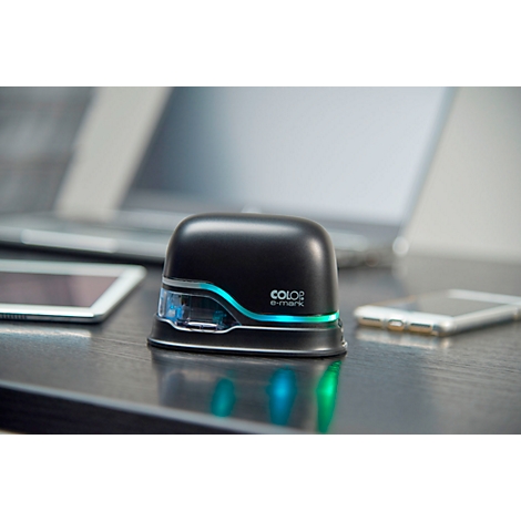 Black Color e-mark stamp on a desk, with a laptop, tablet, and smartphone in the background.