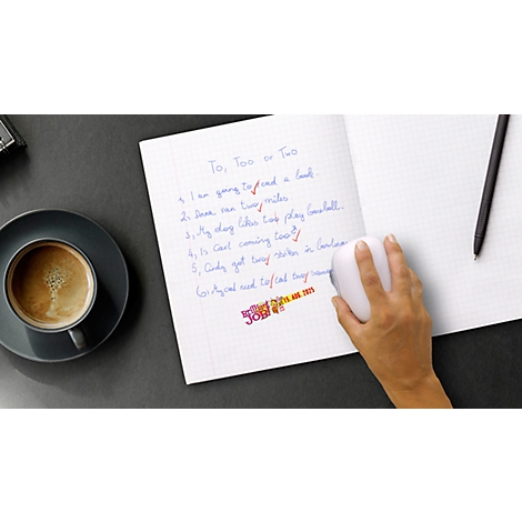 Close-up of notepad with text, hand operating mouse, cup of coffee.