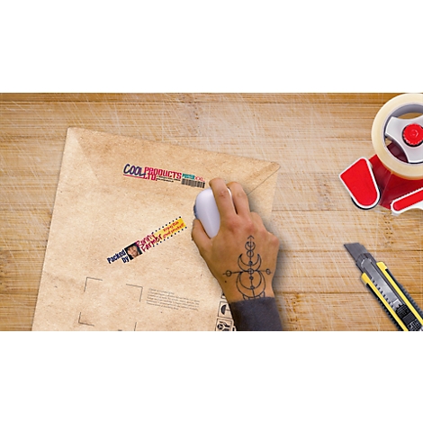 Hand with tattoo holding a mouse over a shipping envelope. Adhesive labels on the envelope, next to it tape and cutter knife.