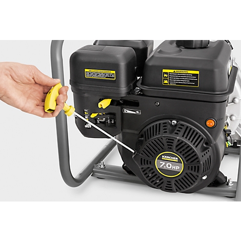 Hand holds a yellow lever on a black water pump with yellow accents. Inscription: Kärcher 7.0 HP.