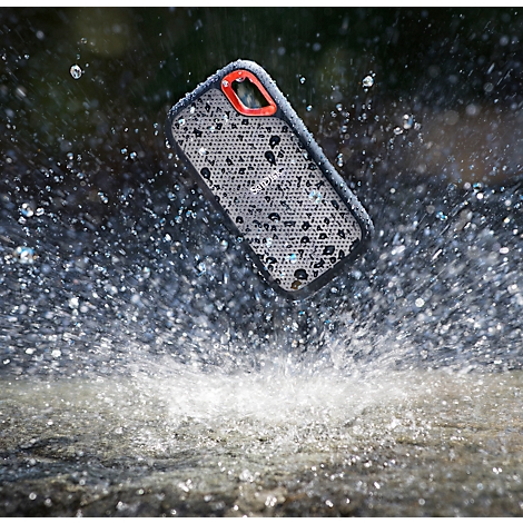 Un smartphone avec une coque tombe dans l'eau. Des gouttelettes d'eau jaillissent. L'étui a un cadre rouge.