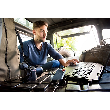 Homme avec ordinateur portable dans la voiture. Appareil photo, disque dur et sac à dos prêts. Travailler à l'extérieur.