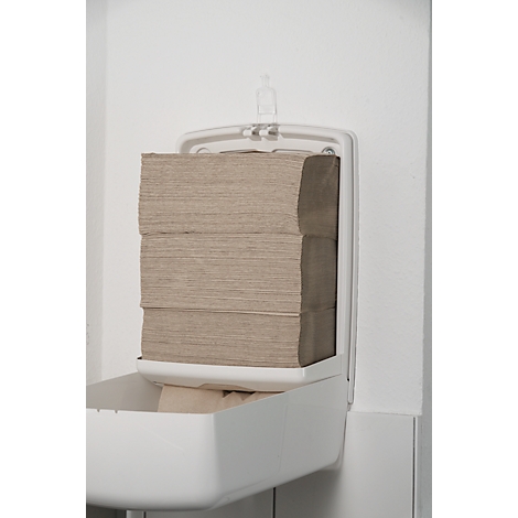 Un distributeur d'essuie-mains en papier blanc sur un mur blanc. Les serviettes sont beiges et empilées.