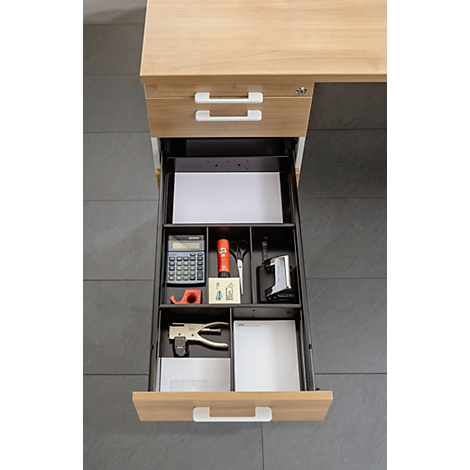 Open desk drawer with office supplies such as calculator, stapler, scissors, paper, and tape.