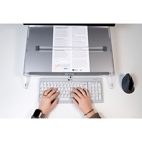 Person typing on a keyboard, in front of a document holder with text. A mouse is to the right.