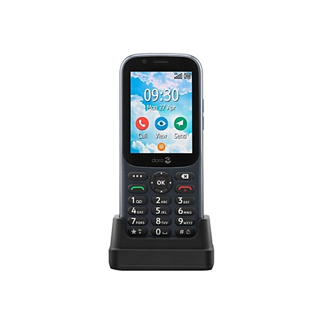 Ein graues Handy mit schwarzer Ladestation. Das Display zeigt Uhrzeit, Datum und Menüsymbole. Tasten und Zahlen sind sichtbar.