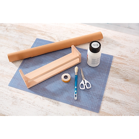 Wooden shelf, glue, paper roll, brush, scissors and tape on a blue surface. For crafts.