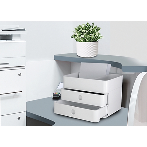 White filing system with two drawers on desk. Plant on top. Printer in the background.