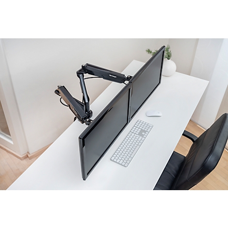Twee monitoren op een witte tafel, vastgehouden door een zwarte monitorarm. Muis, toetsenbord en stoel ernaast.