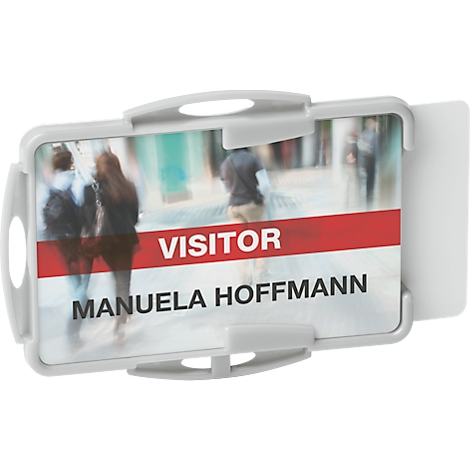 Grauer Ausweis mit der Aufschrift „Visitor Manuela Hoffmann“ vor verschwommenem Hintergrund.