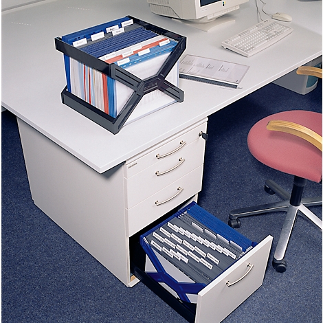 Black file holder with colored file folders on a desk. Drawer open with more files.