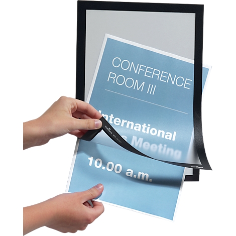 Two hands holding a blue paper with the text "Conference Room III" and "International Meeting". The paper is being removed from a black frame.