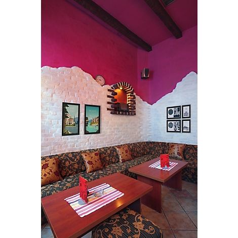 Gezellige restaurant hoek met roze muur, wit baksteen, gestoffeerde banken en houten tafels.