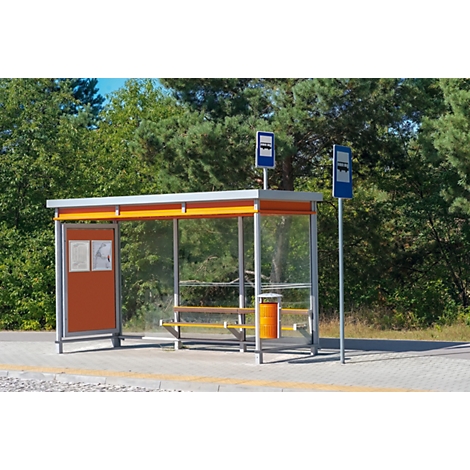 Eine moderne Bushaltestelle mit orangefarbenen Elementen und Glaswänden vor einem Waldrand.