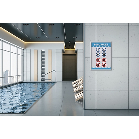 Ein Schild mit Pool-Regeln hängt an der gefliesten Wand eines modernen Hallenbads mit Fensterfront und Liegen.
