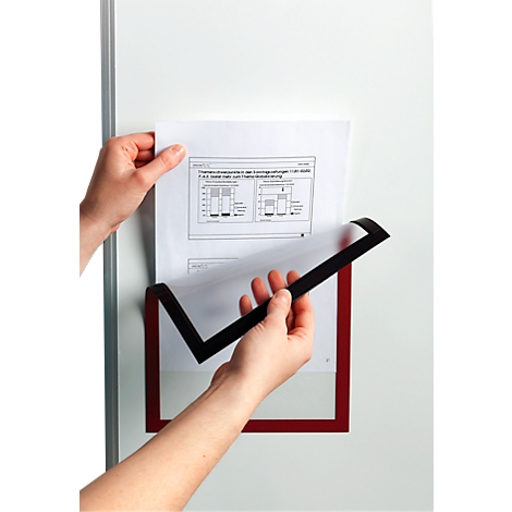 A person inserts a page into a magnetic document pouch. Charts are visible on the sheet.