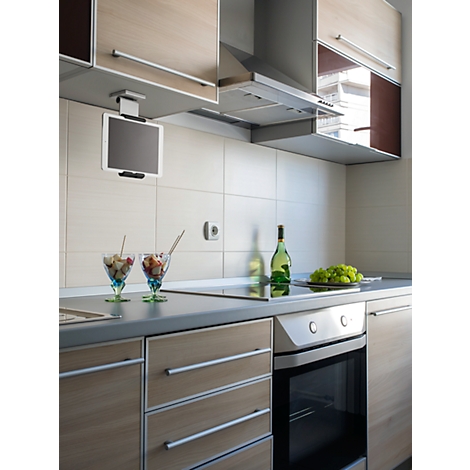 Modern kitchen featuring a tablet, fruit cups, and wine bottles. Light-colored cabinets, dark countertop, appliance buttons.