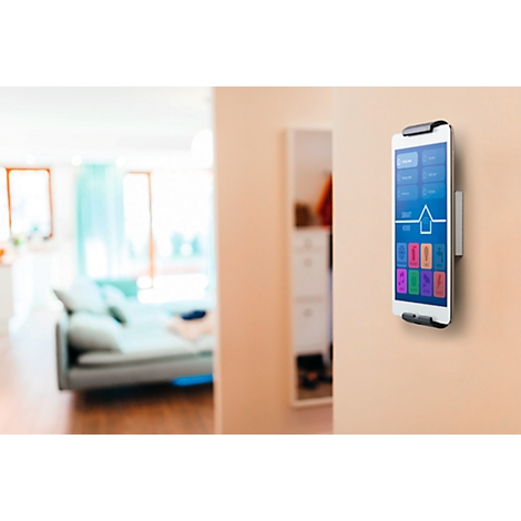 A smartphone mounted on the wall controls a smart home. Various options are displayed on the screen.