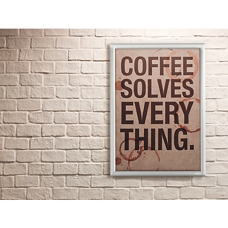 Poster in silbernem Rahmen an einer weißen Ziegelwand mit dem Spruch Coffee solves everything und Kaffeeflecken.