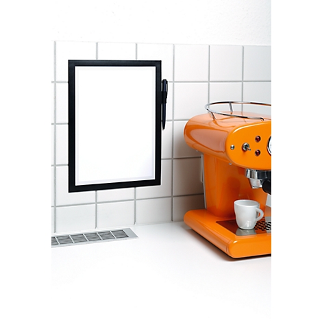 Orange coffee machine with white cup, next to a black board hanging on white tiles.