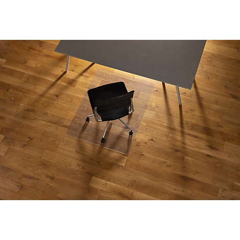 Vista aérea de una silla de oficina, una mesa y una alfombra para silla sobre un piso de madera.