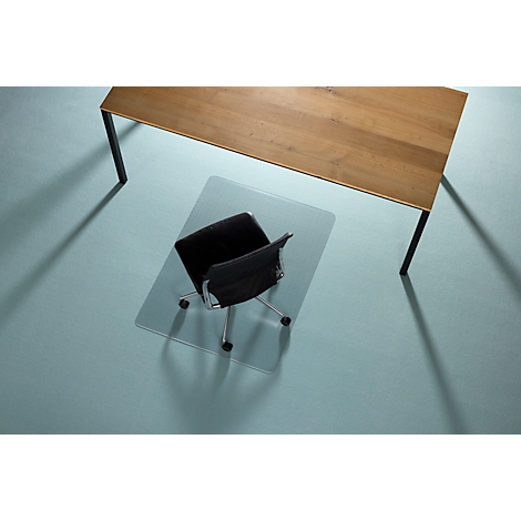 Silla de oficina sobre alfombra protectora transparente debajo de una mesa de madera, vista superior.