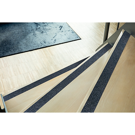 Staircase with anti-slip strips on the steps. Light wood, blue carpet in the background.