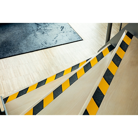 Stairs with yellow and black safety markings. Rectangular carpet at the top left.