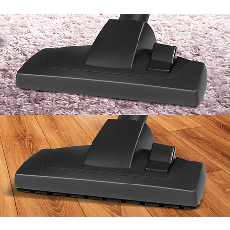 The black brush head of a vacuum cleaner is shown on a carpet and on wood. The nozzle can be seen on the wood.