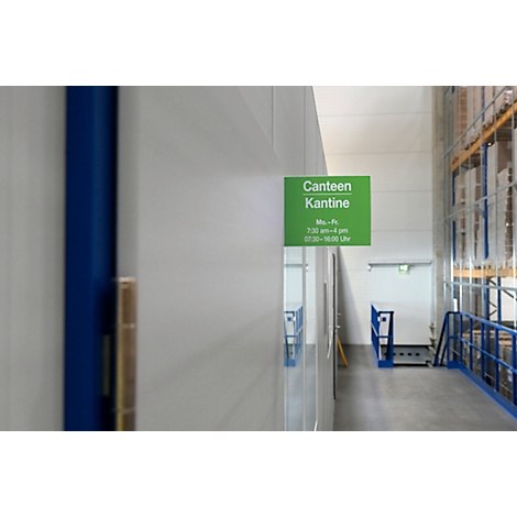 Groen kantinebord met openingstijden. Op de achtergrond een gang en magazijnstellingen.