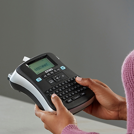Persoon typt op een zwarte DYMO-labelmaker met '6 FEET APART' op het display.