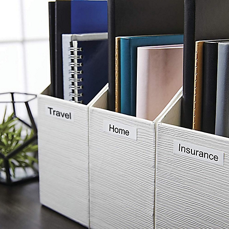 Drei weiße Ordner mit Beschriftungen: Travel, Home, Insurance, gefüllt mit Büchern und Notizbüchern.