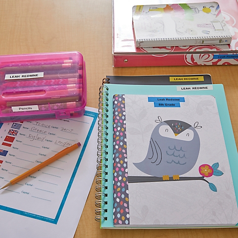 Close-up van schoolspullen: etui, notitieboekjes, potlood, gelabelde mappen.