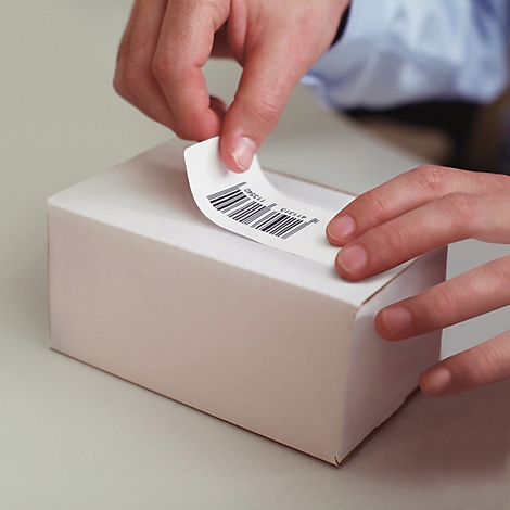 Les mains collent une étiquette de code-barres sur une boîte blanche.